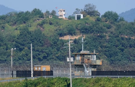 Rival guard posts beside barbed wire topped metal border fence