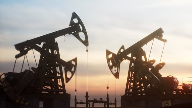 Multiple oil pump jacks working against a dramatic sunset sky. The scene highlights the industrial landscape of energy production, fossil fuels, and the petroleum industry.