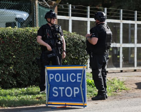 Armed police stand behind a "Police Stop" sign at a cordon outside RAF Fairford