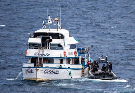 Marines and sailors board a fishing vessel from a small boat during a maritime interdiction at sea