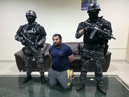 Two soldiers standing with guns and a man on his knees between them