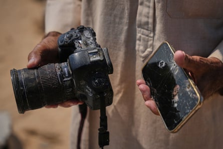 Close-up of hands holding smashed phone and damaged camera