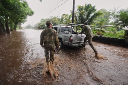 Members of the Hawaii army national guard help a resident leave his home as rainwater from nearby Hurricane Nolo floods a section of Mamalahoa highway on Saturday.