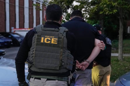 Two federal agents escort a detained man.